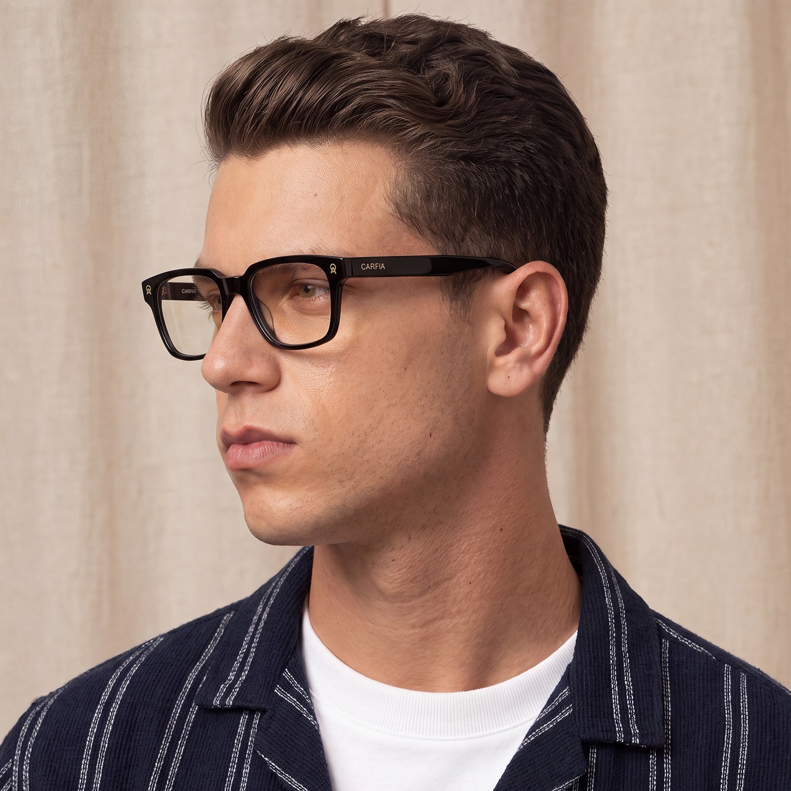 A man wearing black rectangular eyeglasses with a slim bridge and black temples
