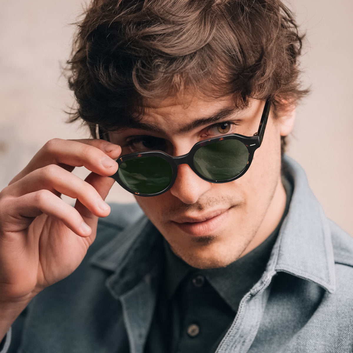 A close-up lifestyle shot of a man wearing round black sunglasses with dark green lenses, holding one lens with his hand CARFIA prescription sunglasses men model